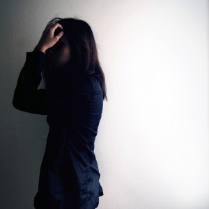 Depressed woman facing wall in shadows